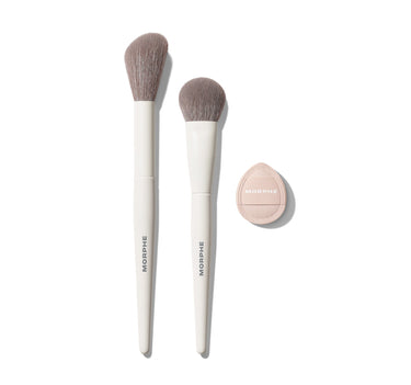 Morphe Blush Layering Tool Trio: two white MORPHE brushes with taupe bristles beside a nude-pink MORPHE compact sponge, shadow view. | Blush Layering Tool trio